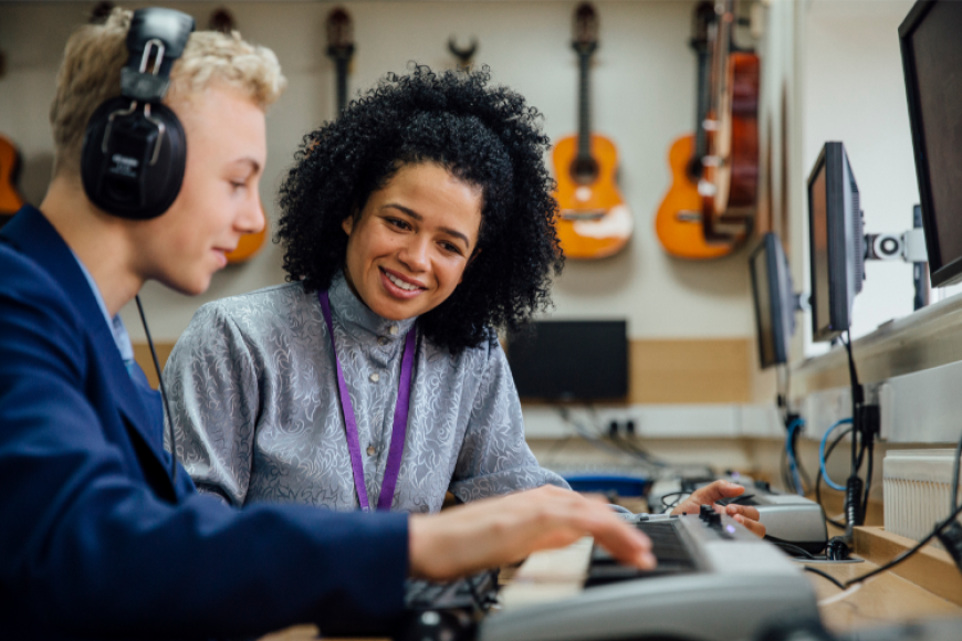 College student receiving instruction on an electronic keyboard.