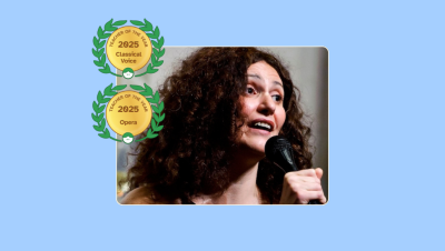 Image of Denise Bayraktar singing into a microphone with her Lessonface Teacher of the Year badges for Classical Voice and Opera