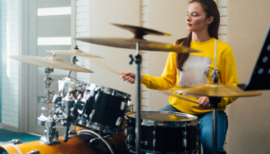 Woman practicing at a drum set.